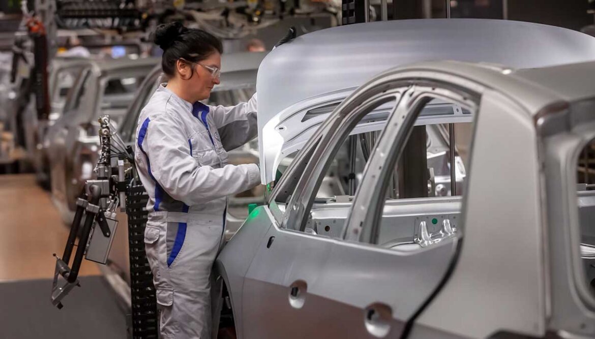 Operaia al lavoro su auto in fabbrica Donna al lavoro per produzione auto