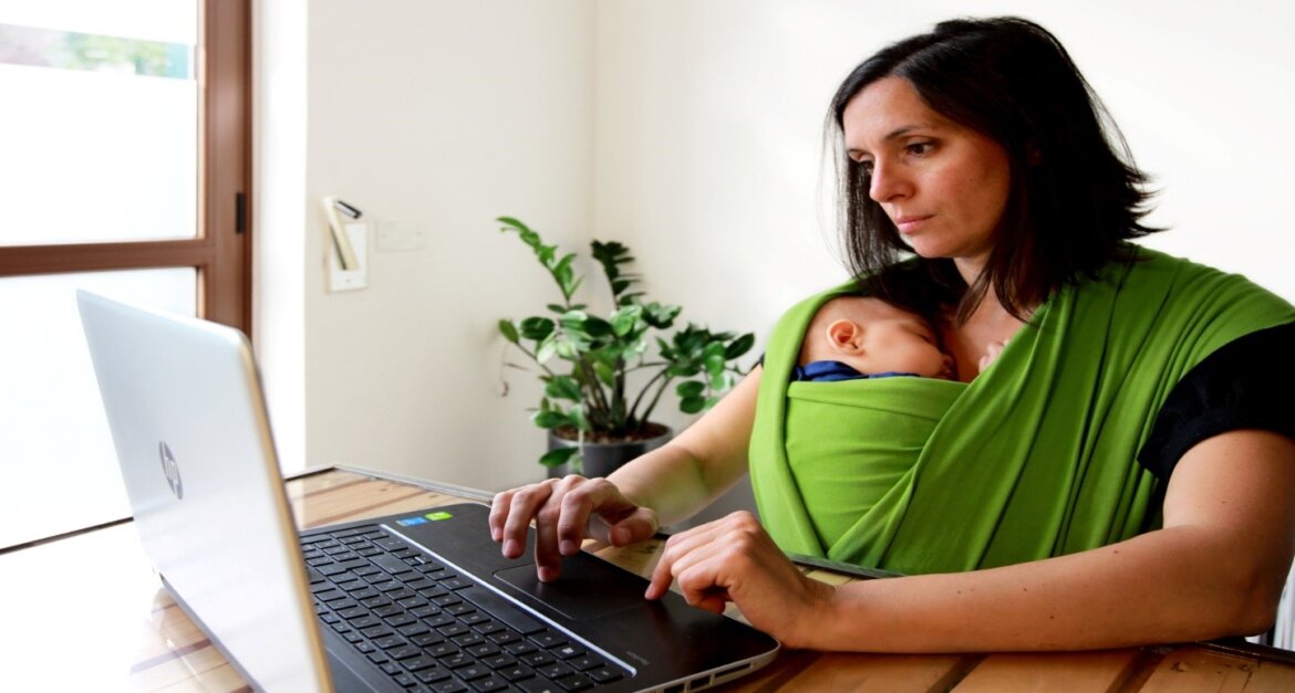Donna al lavoro al pc con bimbo n fascia