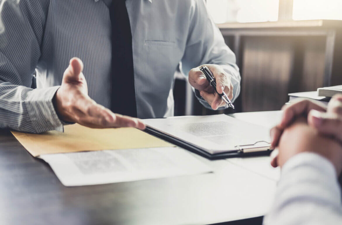 I lavori più richiesti in estate in Emilia Romagna Persone sedute ad una scrivania con contratto di lavoro davanti