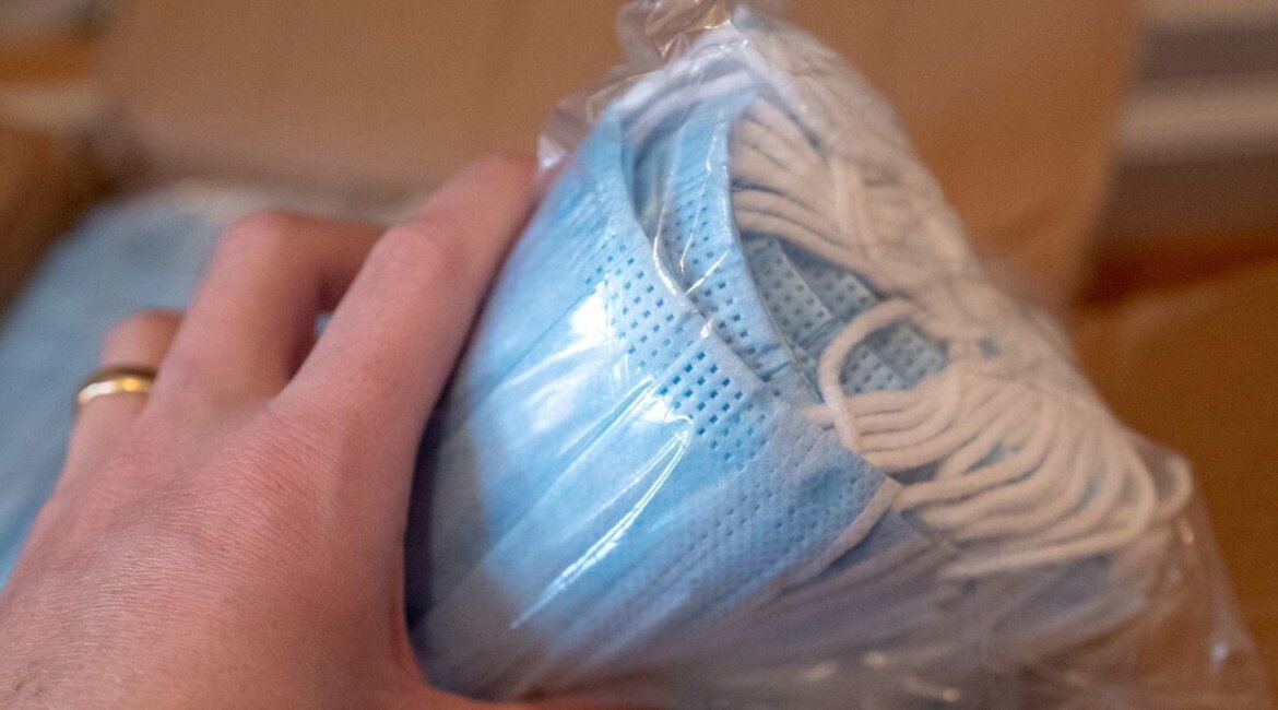 Persona tiene in mano un pacco di mascherine chirurgiche