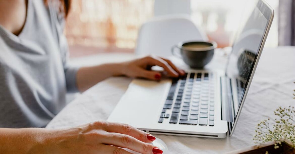 Persona al lavoro con il pc da casa Persona al lavoro al computer con tazza di caffè affianco