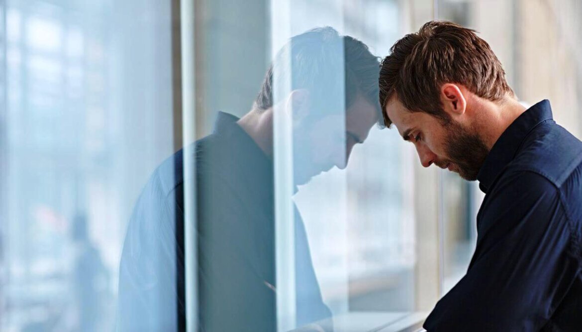 Uomo che appoggia la testa su una finestra