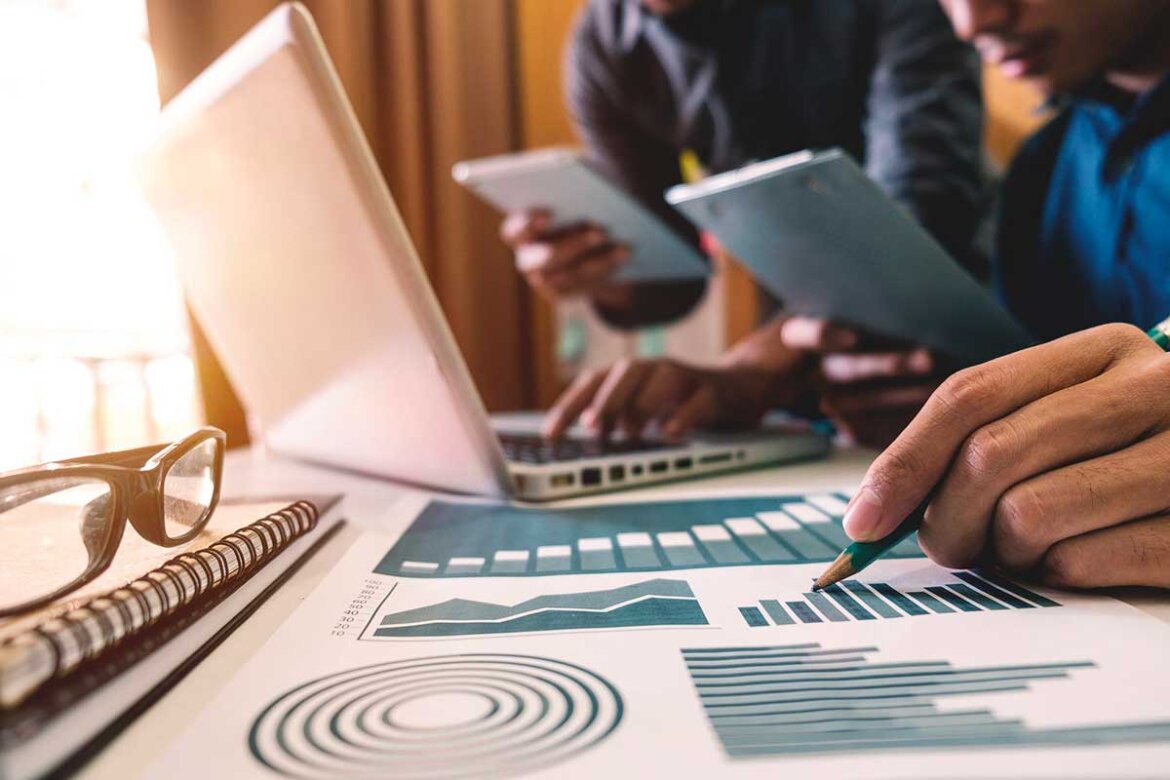 Ragazzi al pc e con grafici su fogli in una foto Ragazzi al lavoro al pc in ufficio