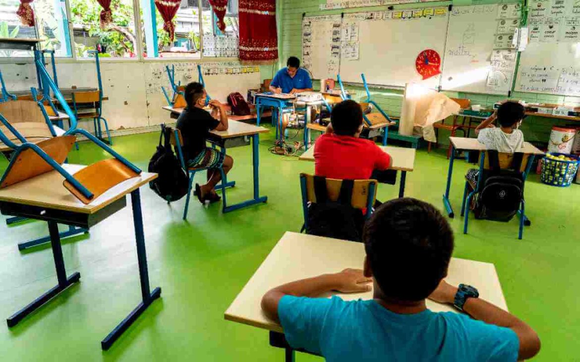 Bambini seduti sui banchi di scuola distanziati Bambini in classe e banchi di scuola separati